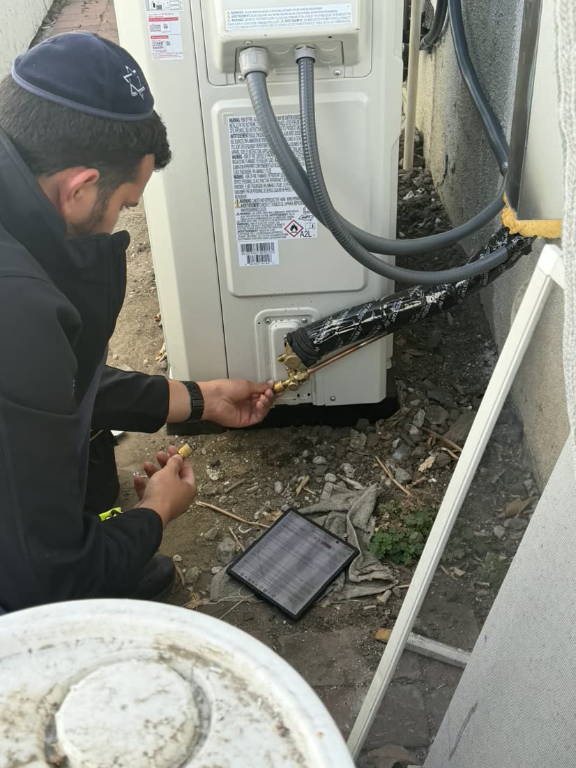 Ben connecting pressure gauges to an outdoor condenser to verify refrigerant charge