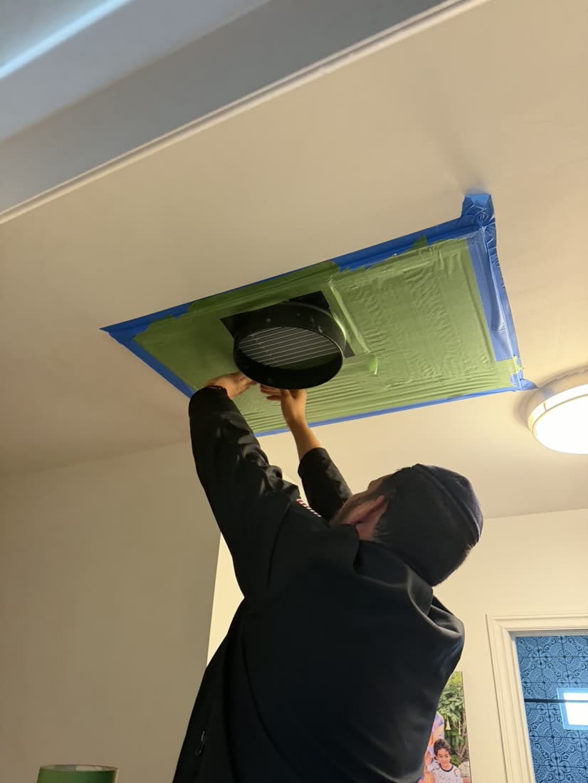 Ben taping off a ceiling register before a duct leakage test